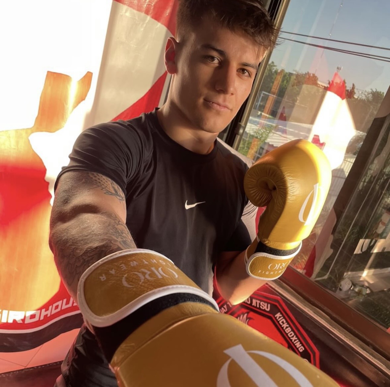 Peleador con guantes dorados ORO frente a la lona del gimnasio
