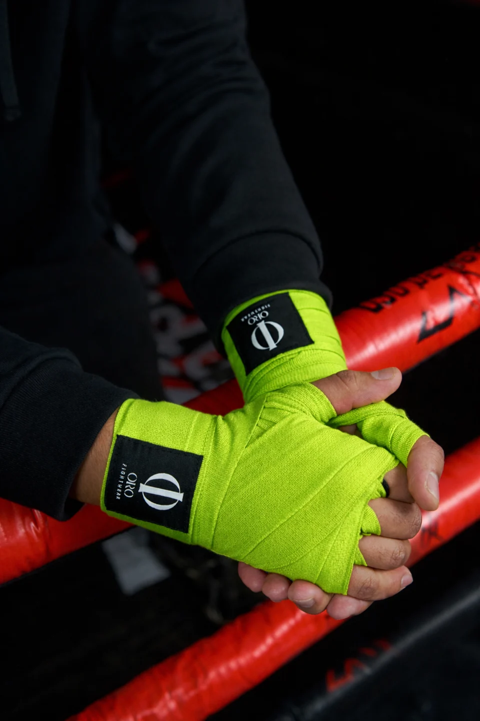 Manos con vendas ORO verdes sobre las cuerdas del ring