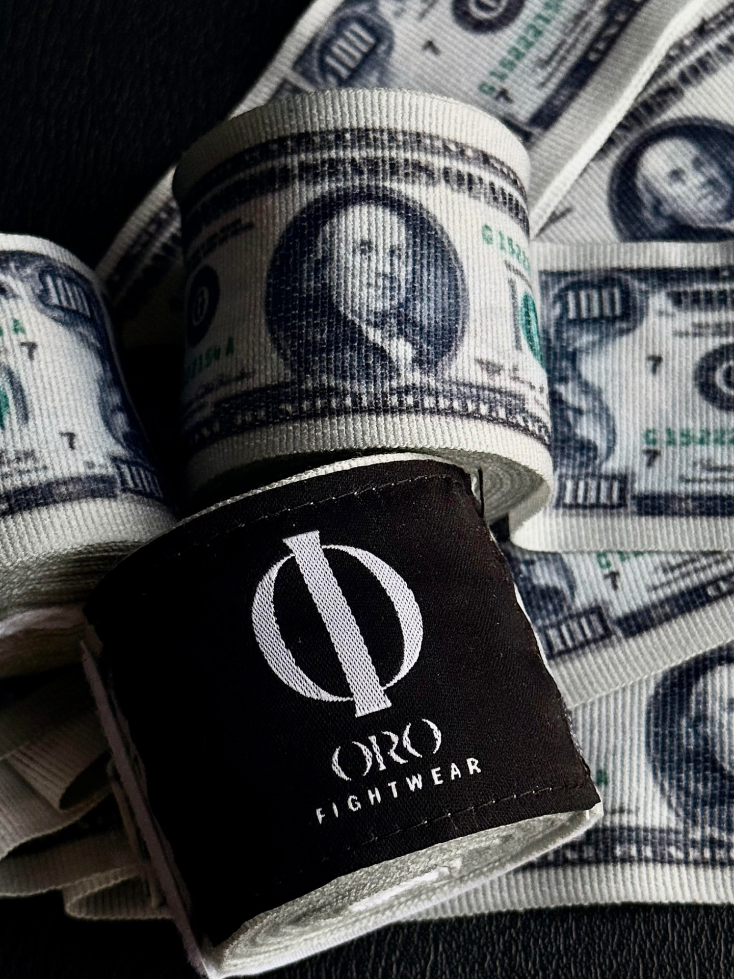 Detalle cercano del material y el parche ORO Fightwear sobre el estampado Dollar