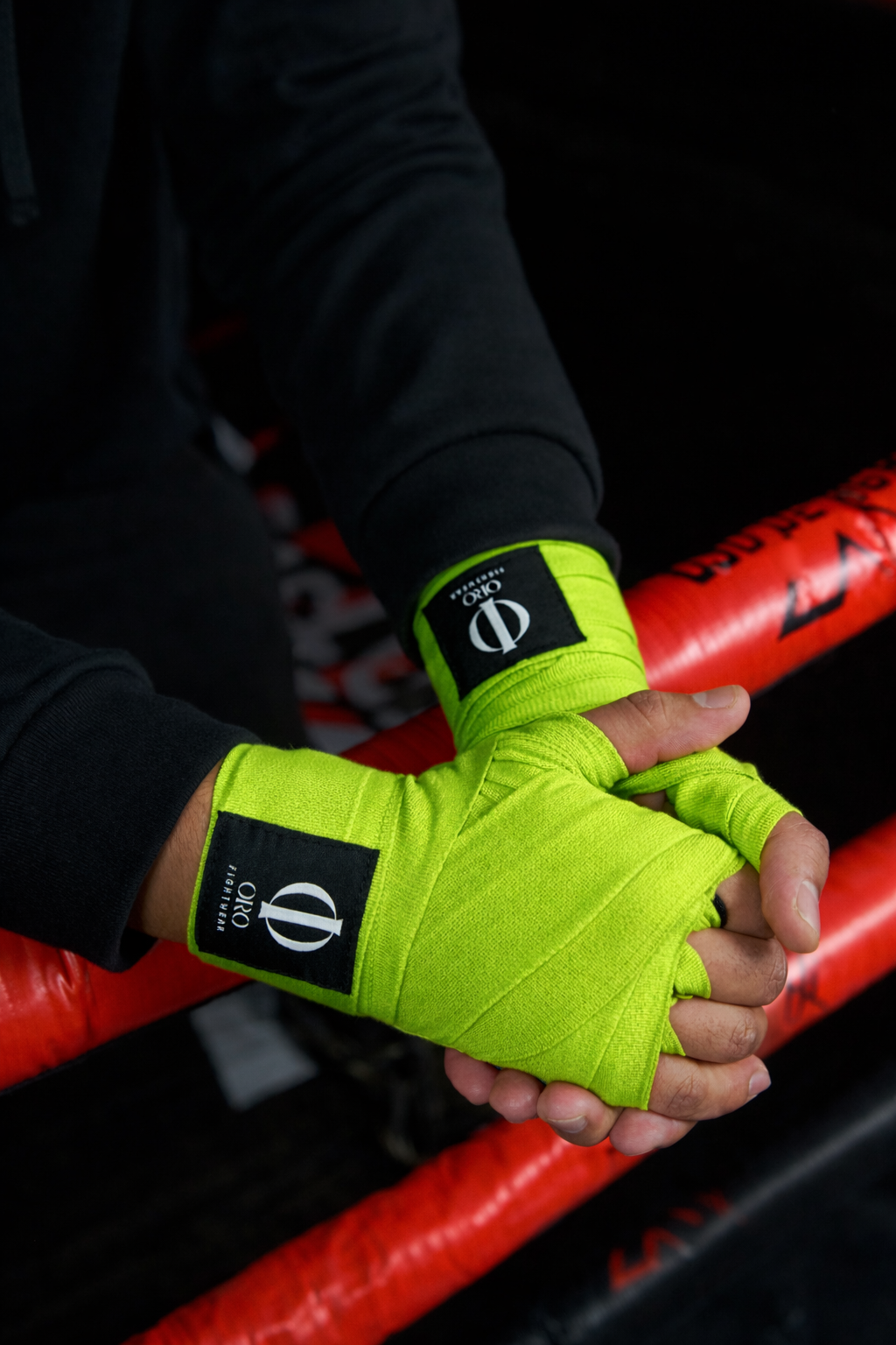 Manos con vendas ORO verdes sobre las cuerdas del ring